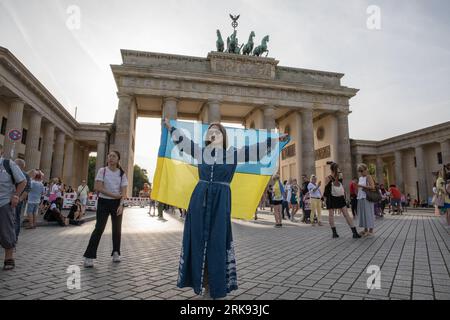 Gli ucraini si riunirono alla porta di Brandeburgo a Berlino il 24 agosto 2023, per celebrare il giorno dell'indipendenza dell'Ucraina. Ma questa non era una festa ordinaria. La folla, un mare di girasoli, bandiere, striscioni e abiti tradizionali ucraini, è arrivata con un messaggio di memoria e resilienza. In un gesto simbolico, i partecipanti tenevano degli specchi, 503 in totale, ciascuno che rifletteva il volto di un bambino perso nella guerra russa contro l'Ucraina. Sotto il sole che tramonta, gli specchi sono serviti come un ricordo inquietante dei 503 bambini ucraini le cui vite sono state bruscamente e spietatamente prese nel conflitto. Ucraino Foto Stock