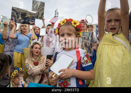 Berlino, Germania. 24 agosto 2023. Gli ucraini si riunirono alla porta di Brandeburgo a Berlino il 24 agosto 2023, per celebrare il giorno dell'indipendenza dell'Ucraina. Ma questa non era una festa ordinaria. La folla, un mare di girasoli, bandiere, striscioni e abiti tradizionali ucraini, è arrivata con un messaggio di memoria e resilienza. In un gesto simbolico, i partecipanti tenevano degli specchi, 503 in totale, ciascuno che rifletteva il volto di un bambino perso nella guerra russa contro l'Ucraina. Sotto il sole che tramonta, gli specchi sono serviti come un ricordo inquietante dei 503 bambini ucraini le cui vite erano bruscamente e spietate Foto Stock