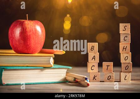 Libri, mele e cancelleria sono appoggiati sul tavolo sullo sfondo di una lavagna nera. Istruzione, 1° settembre, nuovo anno accademico con spazio copia Foto Stock