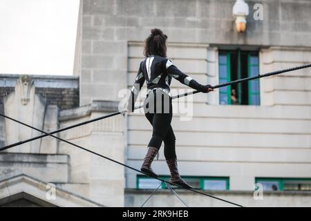 Londra, Regno Unito. 24 agosto 2023. Camminatrice a corda stretta di fama internazionale, Tatiana Mosio Bongonga, sul filo alto, per le prove del suo spettacolo "Open Lines". Con l'aiuto di dodici persone straordinarie provenienti dalla comunità locale, compie una traversata sorprendente, aprendo il GDIF 2023 (Greenwich and Docklands International Festival). L'evento notturno di domani sera celebrerà l'importanza dell'unità collettiva e della speranza. Crediti: Imageplotter/Alamy Live News Foto Stock