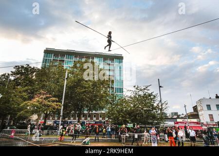 Londra, Regno Unito. 24 agosto 2023. Camminatrice a corda stretta di fama internazionale, Tatiana Mosio Bongonga, sul filo alto, per le prove del suo spettacolo "Open Lines". Con l'aiuto di dodici persone straordinarie provenienti dalla comunità locale, compie una traversata sorprendente, aprendo il GDIF 2023 (Greenwich and Docklands International Festival). L'evento notturno di domani sera celebrerà l'importanza dell'unità collettiva e della speranza. Crediti: Imageplotter/Alamy Live News Foto Stock