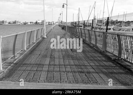 Bianco e nero, molo, passerella. Una passerella in legno vicino al porticciolo nel porto di Gosport. Foto Stock