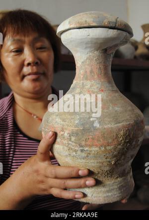 Bildnummer: 54294774  Datum: 13.08.2010  Copyright: imago/Xinhua (100813) -- SHIJIAZHUANG, Aug. 13, 2010 (Xinhua) -- A worker shows an entique pottery pot excavated from tombs dating back to the Han Dynasty (202 BC-220 AD) in Xingtai City, north China s Hebei Province. Archeologists have unearthed more than 260 antiques, such as spade-shaped coins, brass bells and pottery vessels, from 93 tombs of the Warring States (475-221 BC) period and the Han Dynasty in Xingtai s Zhangduo Village. The move was to protect the antiques from the potential effect brought by China s ongoing project of divertin Stock Photo