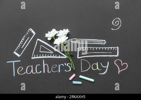 Beautiful flowers with drawings and text TEACHER'S DAY on black chalkboard Stock Photo