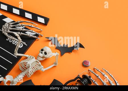 Clapperboard con diversi decori di Halloween su sfondo arancione Foto Stock