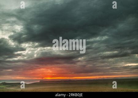 Beachy Head, Eastbourne, Sussex, Regno Unito. 24 agosto 2023. Breve scorcio del tramonto sotto le nuvole tempestose mentre la nebbia marina si muove. Foto scattata dall'area di Beachy Head che guarda a ovest sulle scogliere di Birling Gap e Seven Sisters. Faro di Belle Tout a sinistra della foto. Credito: David Burr/Alamy Live News Foto Stock