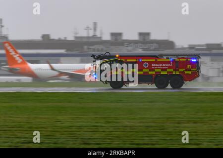 Un camion dei vigili del fuoco Rosenbauer Panther dell'aeroporto di Edimburgo scende lungo Una pista bagnata da pioggia durante un incidente di emergenza con Un A350 della Qatar Airways Foto Stock