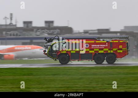 Un camion dei vigili del fuoco Rosenbauer Panther dell'aeroporto di Edimburgo scende lungo Una pista bagnata da pioggia durante un incidente di emergenza con Un A350 della Qatar Airways Foto Stock