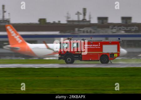 Un camion dei vigili del fuoco Scania dell'aeroporto di Edimburgo scende lungo Una pista bagnata dalla pioggia durante un incidente di emergenza con Un A350 della Qatar Airways Foto Stock