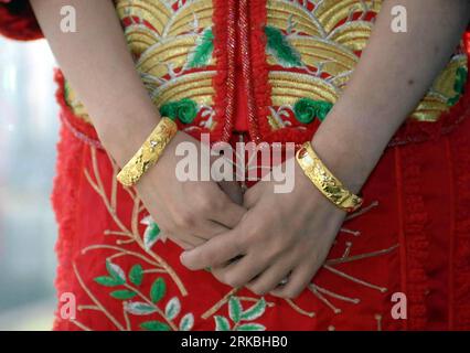 Bildnummer: 54562517 Datum: 24.10.2010 Copyright: imago/Xinhua (101025) - HONG KONG, 25 ottobre 2010 (Xinhua) -- la sposa è vista indossare un paio di bracciali d'oro scolpiti con drago e fantasie phoenix durante una tradizionale cerimonia di nozze cinese a Hong Kong, 24 ottobre 2010. L'usanza del matrimonio cambia dato che è popolare oggigiorno per le giovani coppie avere una tradizionale cerimonia cinese al mattino e una in stile occidentale in chiesa nel pomeriggio. (Xinhua/li Qiuchan) (cxy) CHINA-HONG KONG-CUSTOM-WEDDING (CN) PUBLICATIONxNOTxINxCHN Gesellschaft kbdig xcb 2010 quer o0 Hochzeit AR Foto Stock