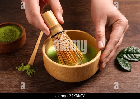 Donna che prepara il tè matcha al tavolo di legno, primo piano Foto Stock