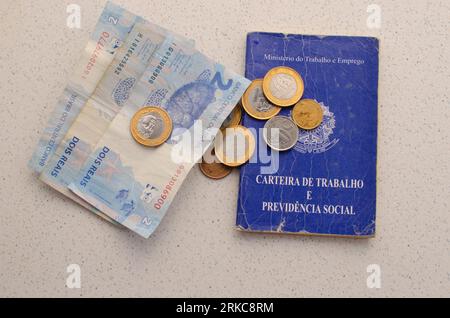 Scheda di lavoro per il Brasile. Traduzione - Repubblica Federativa del Brasile, Ministero del lavoro. Scheda di lavoro per il Brasile con soldi sul lato. simboleggiando l'importanza Foto Stock