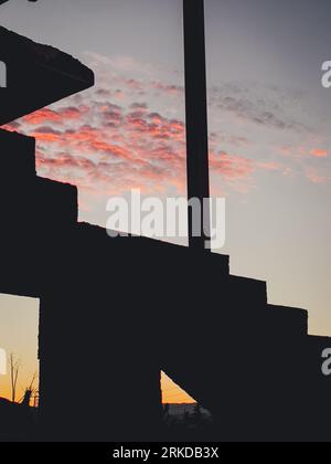 An elegant silhouette of a cross against the backdrop of a dramatic cloudy sky at sunset Stock Photo