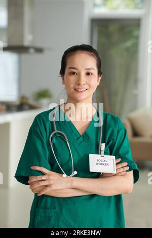 Ritratto di un giovane assistente sociale asiatico sorridente in uniforme verde Foto Stock