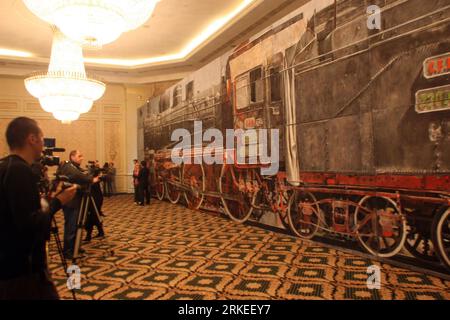 Bildnummer: 55248330  Datum: 08.04.2011  Copyright: imago/Xinhua (110408) -- BUCHAREST, April 8, 2011 (Xinhua) -- Reporters stand in front of the life-size canvas painting depicting the biggest steam locomotive in Romania, an 1889 Pacific 230 series, in Bucharest, capital of Romania, April 8, 2011. The painting by Romanian artist Alexandru Bunescu measures 20 meters in length and 4.5 meters in height. It will be auctioned next week and is widely expected to reach a value of up to 60,000 euros. (Xinhua/Gabriel Petrescu) (wjd) ROMANIA-BUCHAREST-PAINTING-LOCOMOTIVE PUBLICATIONxNOTxINxCHN Gesellsc Stock Photo