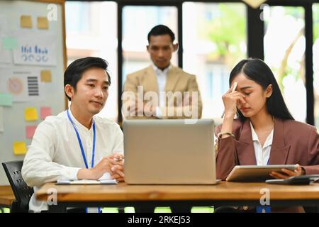 Dipendenti maschi e femmine stressati insoddisfatti dei risultati di lavoro e di un capo rigoroso in background Foto Stock