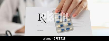 Il medico femminile mostra in bianco carta da prescrizione e pillole mediche. Foto Stock