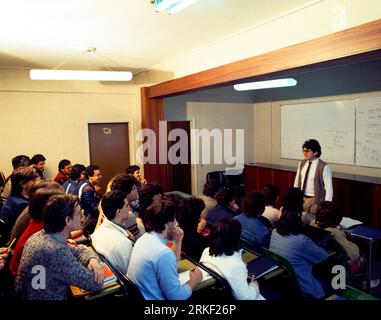 Docente in piedi di fronte alla lavagna bianca in classe di studenti dell'università Foto Stock