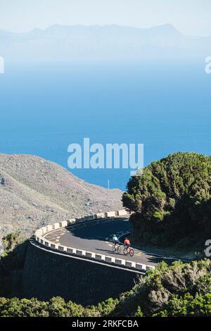 Due ciclisti hanno visto la strada tortuosa con l'oceano sullo sfondo Foto Stock