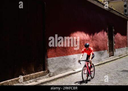 Giri in bicicletta su strada di ciottoli nella città coloniale sullo sfondo rosso Foto Stock