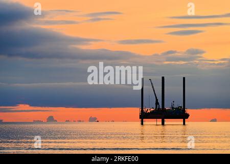 Carro di prova di perforazione con nuvole dorate al largo della costa del Northumberland Mare del Nord all'alba con cielo e mare dall'aspetto caldo Foto Stock