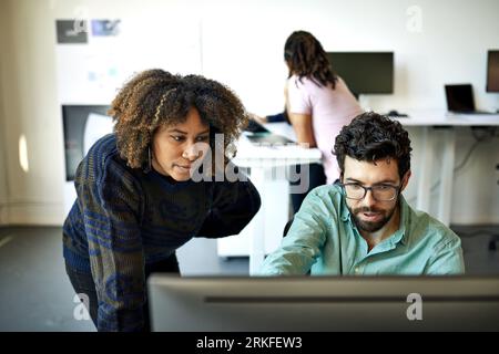 Vista dall'alto di un uomo d'affari che spiega a una donna d'affari tramite un computer desktop in ufficio Foto Stock