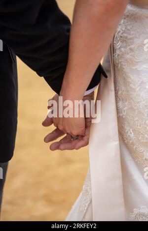 Sposa e sposo che si tengono per mano dopo la cerimonia Foto Stock