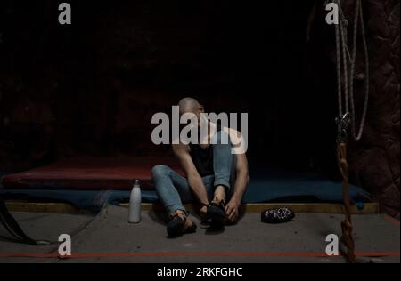 uomo che indossa le scarpe da arrampicata e calca le mani Foto Stock