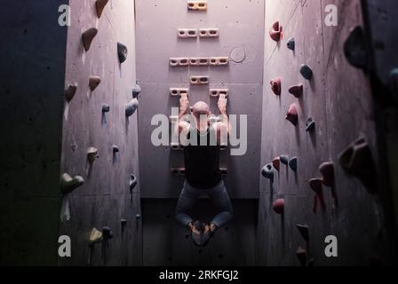 uomo forte che si esercita su una parete per arrampicata facendo tiri in su Foto Stock