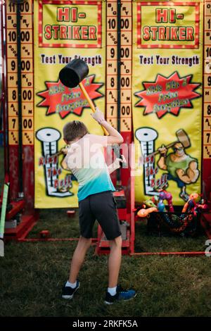 Ragazzo che gioca alla partita di carnevale del martello alla fiera della contea Foto Stock