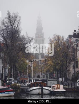 Amsterdam, Paesi Bassi - novembre 27 2022: La Zuiderkerk Tower di Amsterdam in una nebbiosa mattinata autunnale con foglie dorate che cadono dagli alberi. Foto Stock