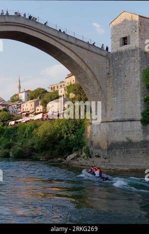 Motoscafo/gommone sul fiume Neretva mentre la gente visita lo Stari Most (Ponte Vecchio) nella città di Mostar, Bosnia ed Erzegovina, 20 agosto 2023. Foto Stock