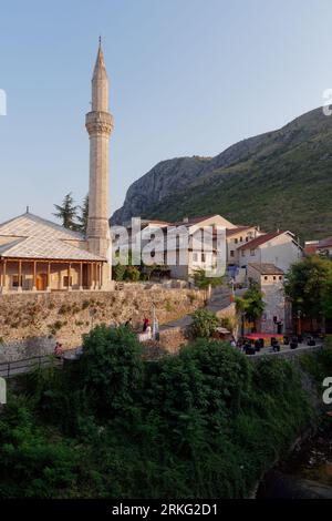 L'esterno della moschea Hadži Kurt è circondato da case e montagne nella città di Mostar, Bosnia ed Erzegovina, 20 agosto 2023. Foto Stock