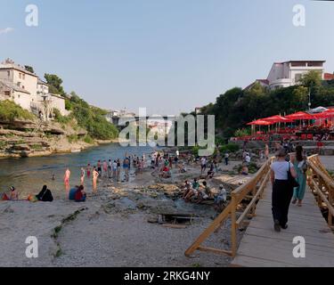 Persone sulla spiaggia lungo il fiume Neretva nella città di Mostar, Bosnia ed Erzegovina, 21 agosto 2023. Foto Stock