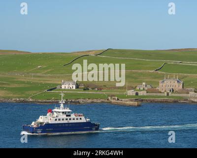 A small ship navigating the calm waters of a serene bay in Shetland, UK Stock Photo