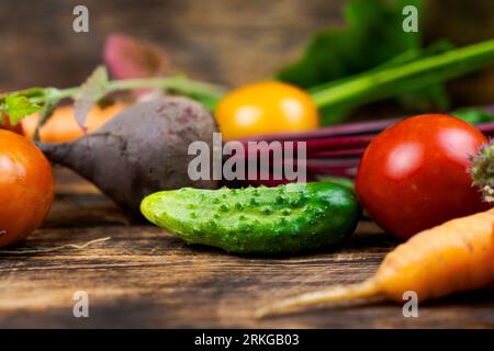 verdure fresche dal giardino carote e barbabietole, pomodori e cetrioli su un vecchio sfondo di legno Foto Stock