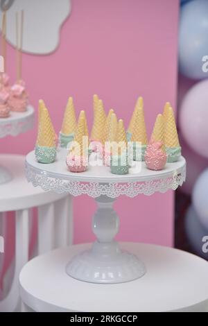 An image of a dessert setup featuring a variety of ice cream cones arranged on a cake stand atop a plate Foto Stock