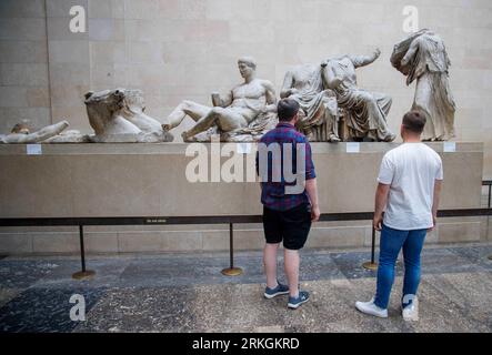 Londra, Regno Unito. 25 agosto 2023. I visitatori del British Museum osservano i marmi di Elgin nelle gallerie del Partenone. Un membro del personale è stato licenziato e si dice che almeno 1.000 pezzi sono mancanti dalla collezione del museo. Gli archeologi greci sostengono che i furti del British Museum mostrano che i marmi di Elgin non sono sicuri e dovrebbero essere restituiti in Grecia. Mancano oggetti come oro, gioielli e pietre preziose semi-preziose. Crediti: Mark Thomas/Alamy Live News Foto Stock