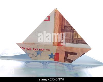 A close-up image of a sailing boat from a fifty euro bill folded. waves from two twenty-euro bills Foto Stock