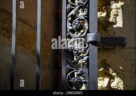 Antico cancello d'ingresso in ferro battuto realizzato a mano contro un muro di pietra a Cefalù Sicilia, Italia. Foto Stock