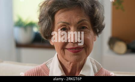 Headshot pensive grandmother senior woman looking distance away turn to camera old mature female elderly granny indoors at home smiling happy portrait Foto Stock