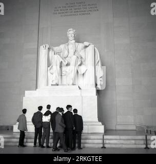 Anni '1960, storico, un gruppo di giovani che guardano la grande statua in marmo di Abraham Lincoln, il XVI presidente degli Stati Uniti, all'interno del Lincoln Memorial a Washington DC, USA. Foto Stock