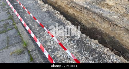Riparazione stradale. Strada circondata da nastro rosso e bianco. Nessuna entrata. Foto Stock