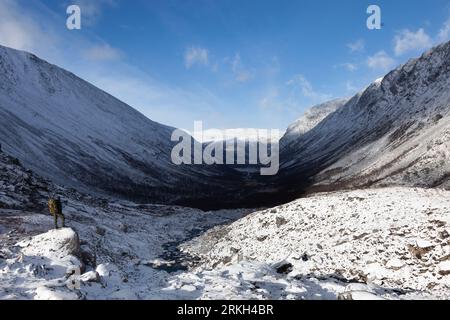 A stunning winter landscape featuring snow-capped mountains under the cloudy sky Stock Photo