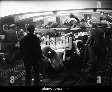 La troupe della telecamera ha girato il carrello sopra il tavolo con i commensali sul set della barca durante le riprese di un film sonoro francese tardo muto/primo, non identificato, intorno al 1930 Foto Stock