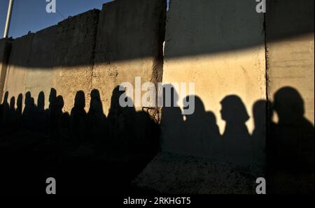 Bildnummer: 55833465  Datum: 26.08.2011  Copyright: imago/Xinhua (110826) -- WEST BANK, Aug. 26, 2011 (Xinhua) -- Shadows of Palestinian women appear on an Israeli separation wall as they wait at the Israeli checkpoint of Qalandiya near the West Bank city of Ramallah to cross into Jerusalem to attend the last Friday prayers of the Islamic holy month of Ramadan at al-Aqsa Mosque, Aug. 26, 2011. (Xinhua/Fadi Arouri) MIDEAST-WEST BANK-RAMADAN-LAST FRIDAY PUBLICATIONxNOTxINxCHN Gesellschaft Westjordanland Nahostkonflikt Grenzposten Grenze Kontrolle Personenkontrolle xns 2011 quer  o0 Grenzkontroll Stock Photo