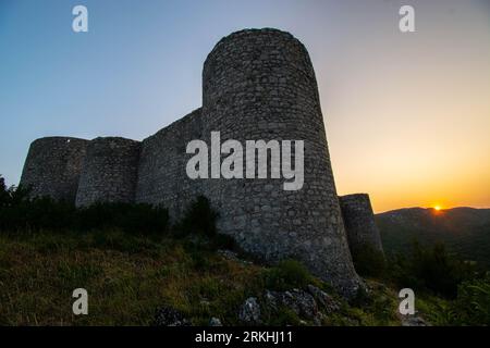 Un'immagine mozzafiato di una torre di castello in pietra stagliata contro un vivace cielo al tramonto Foto Stock