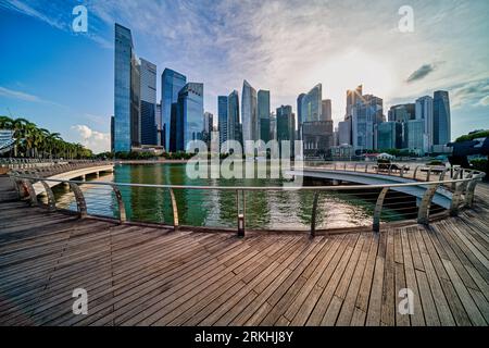 Una vista pittoresca dello skyline del centro di Singapore vista dalla Marina, con un molo che si affaccia sulle acque fisse della baia Foto Stock
