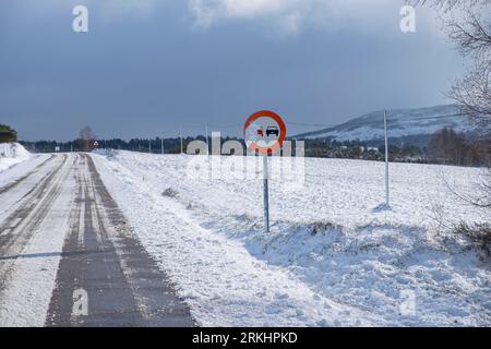 Un primo piano di una strada asfaltata ghiacciata in un paesaggio innevato invernale Foto Stock