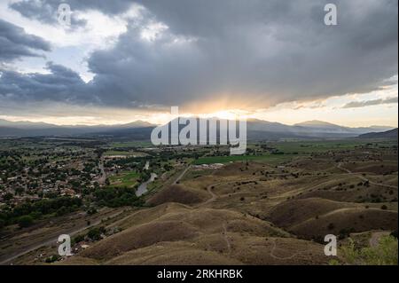 Un paesaggio desertico mozzafiato caratterizzato da incredibili sfumature di rosa, arancione e giallo mentre il sole tramonta su dolci colline in lontananza Foto Stock